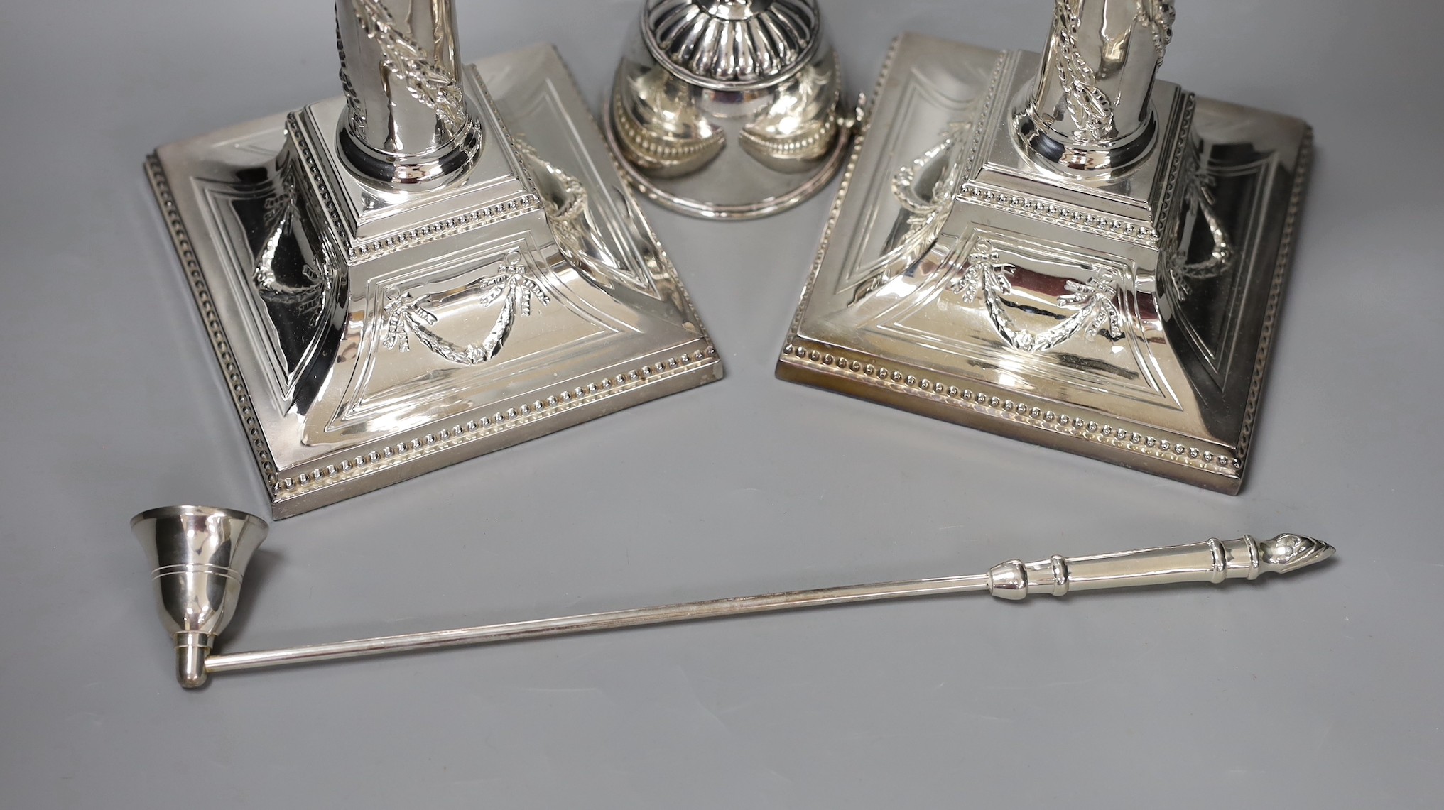 A pair of silver plated candlesticks, a plated wine funnel and a plated candle extinguisher, Plated candlesticks 34 cms high.